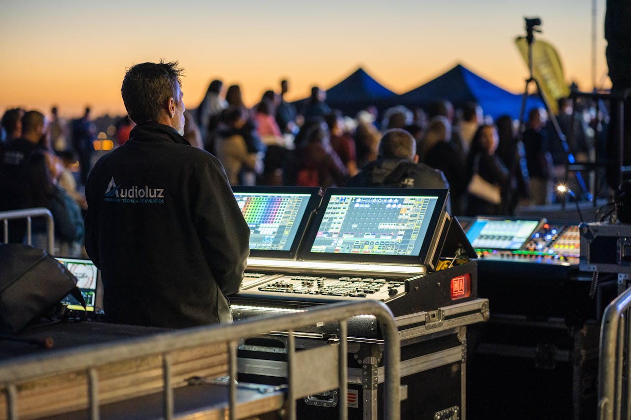 Home Technician managing sound and lighting panels during an outdoor event at sunset.